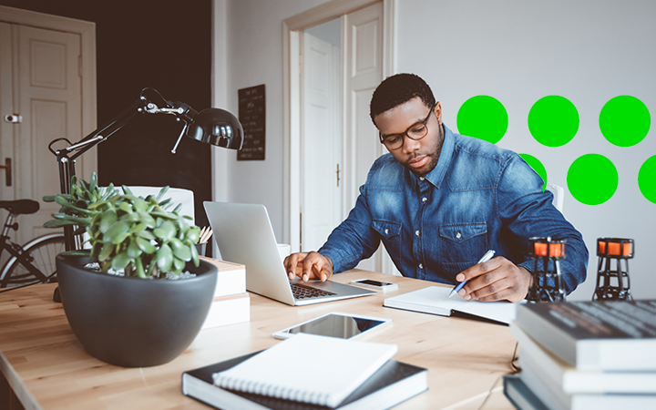 Man working at his desk, writing using his laptop and being safe