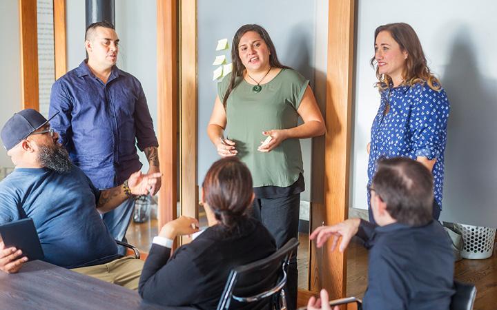 Group of people in a room stand and sit around talking