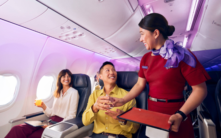 Virgin Australia cabin crew serving drinks to passengers in Business Class