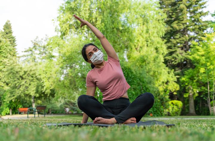 Woman doing yoga with mask on.