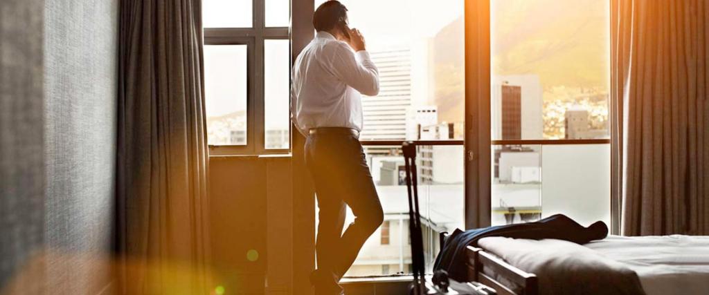 Businessman talking on phone in a hotel room looking outside the window