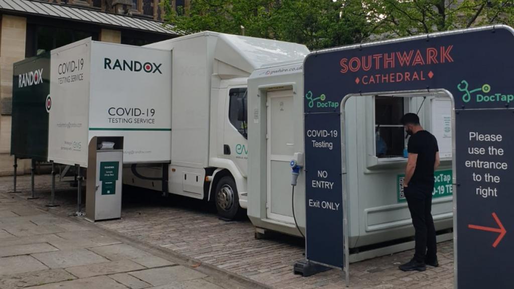 Outdoor COVID testing facility at London's Southwark Cathedral - a truck and entrance are shown while a man stands at the window to be tested