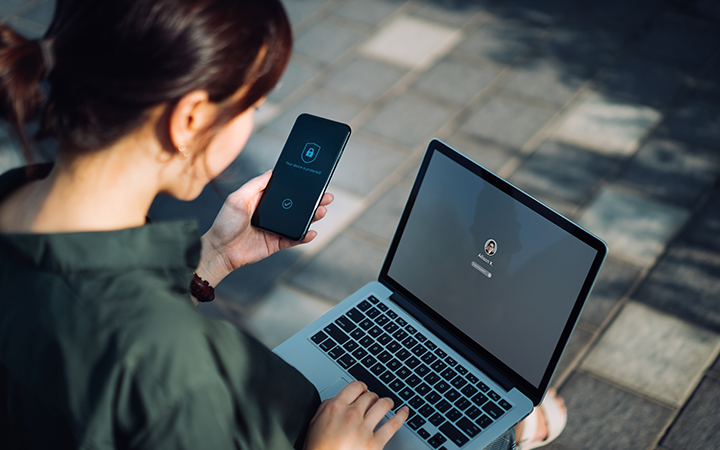 A woman working across a laptop and smartphone representing how artificial intelligence can streamline your business processes and enhance productivity.