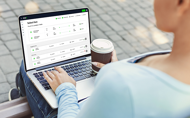 Person on outdoor patio holding coffee, viewing a county transport data dashboard on a laptop