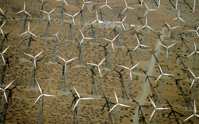 Aerial view of numerous wind turbines in a desert landscape.
