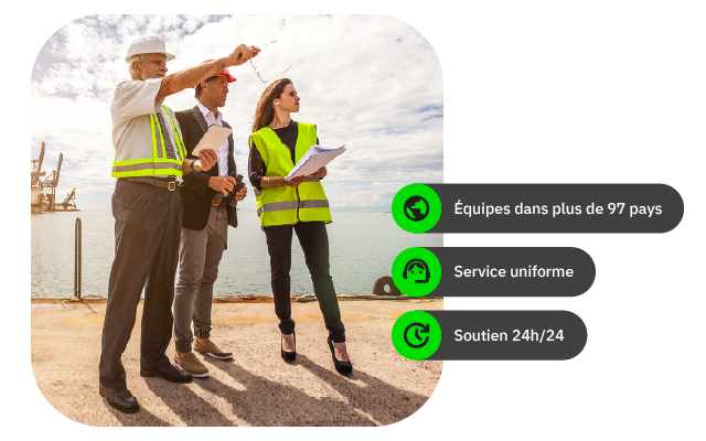 Trois personnes en vêtements de chantier discutent près d'un port sous un ciel nuageux.