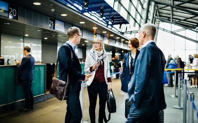 Business professionals conversing in a modern airport terminal.