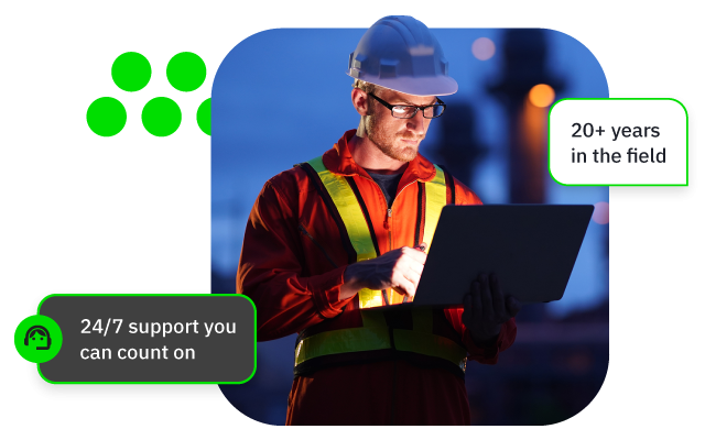 Construction worker in hard hat and reflective vest checks tablet at night on site