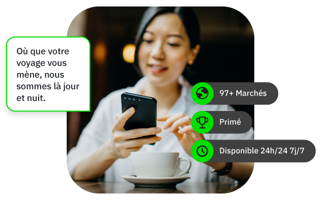 Femme souriante utilisant un téléphone portable, tasse de café devant elle.