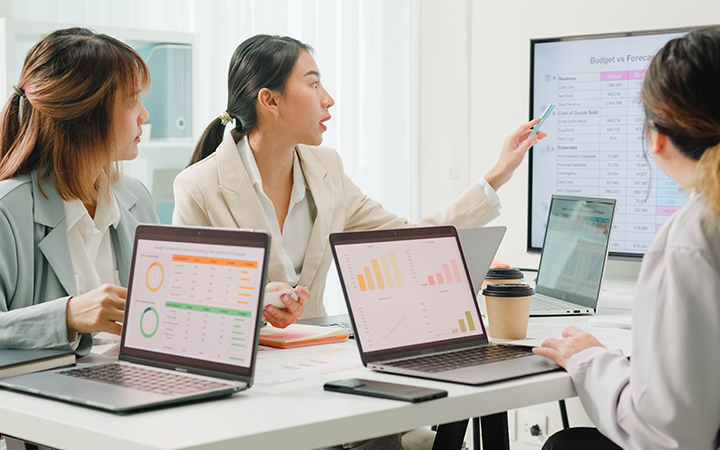 A group of female colleagues gather round a computer screen looking at graphs and data