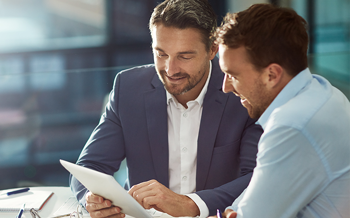 two businessmen looking over information on tablet