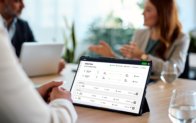 A close-up of a tablet displaying a user interface during a business meeting.
