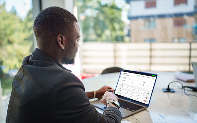 Man in a suit working on a laptop at a bright indoor workspace.