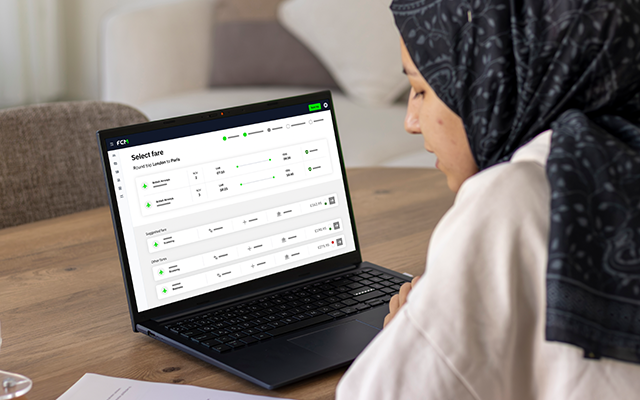 Woman in a headscarf using a laptop, focused on a digital interface.
