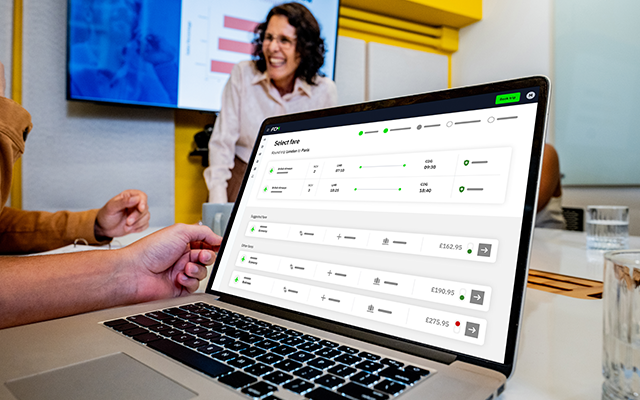 A laptop displaying a software interface with a person smiling in the background.