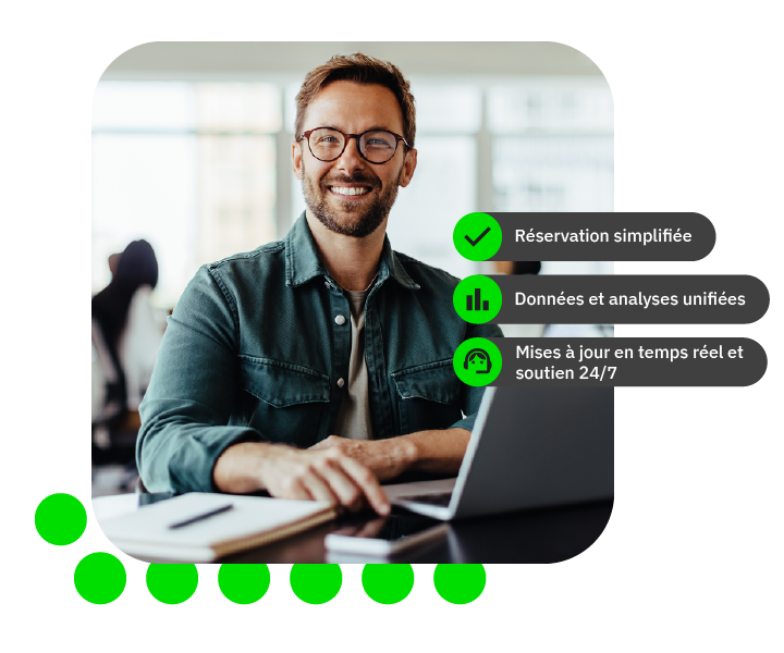 Homme souriant devant un ordinateur portable dans un bureau moderne.