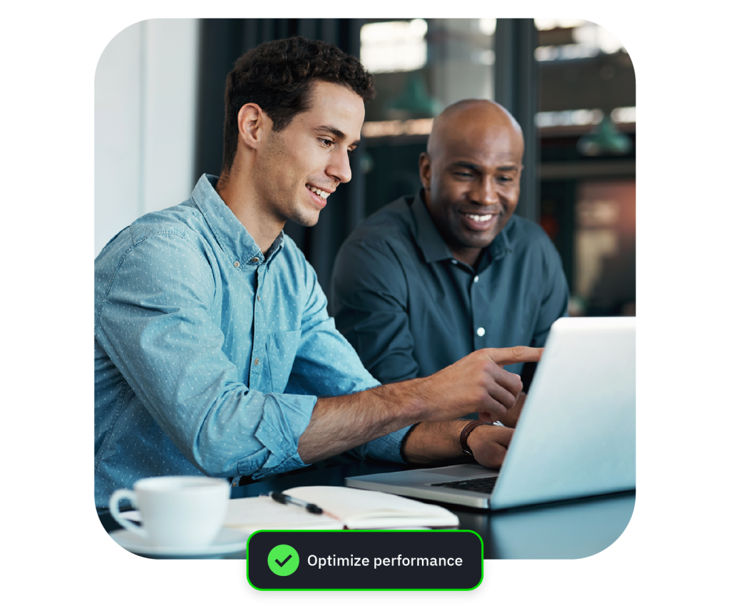 Two coworkers smiling and collaborating over a laptop in a bright office cafe