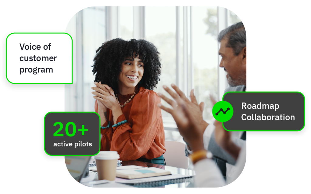 Three coworkers smiling in a meeting, overlays: customer program, 20+ pilots, Roadmap Collaboration