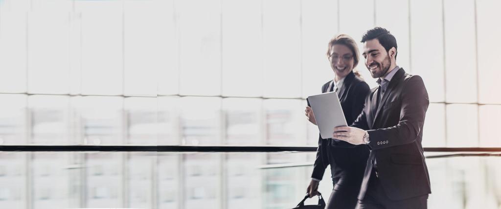 Business man with tablet in hand and business woman with luggage walking in the airport together