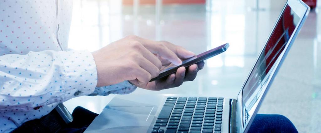 Business man checking his phone while sitting on front of his laptop