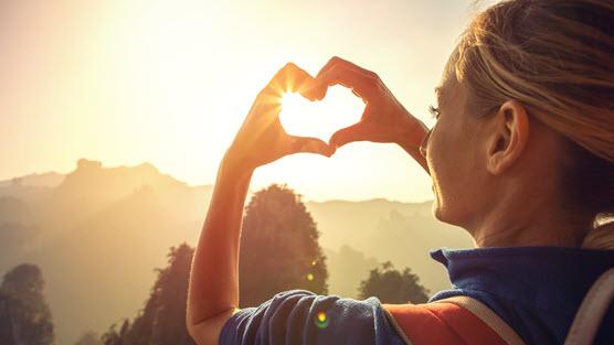 women with heart hands in the sun