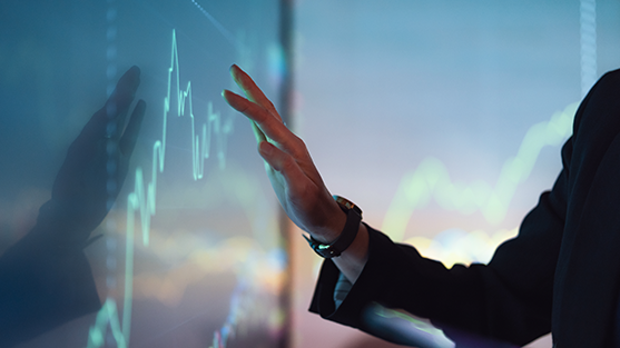 A business professional gestures towards a digital financial graph on a screen.