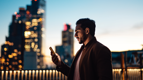 man holding phone with tall buildings in the background